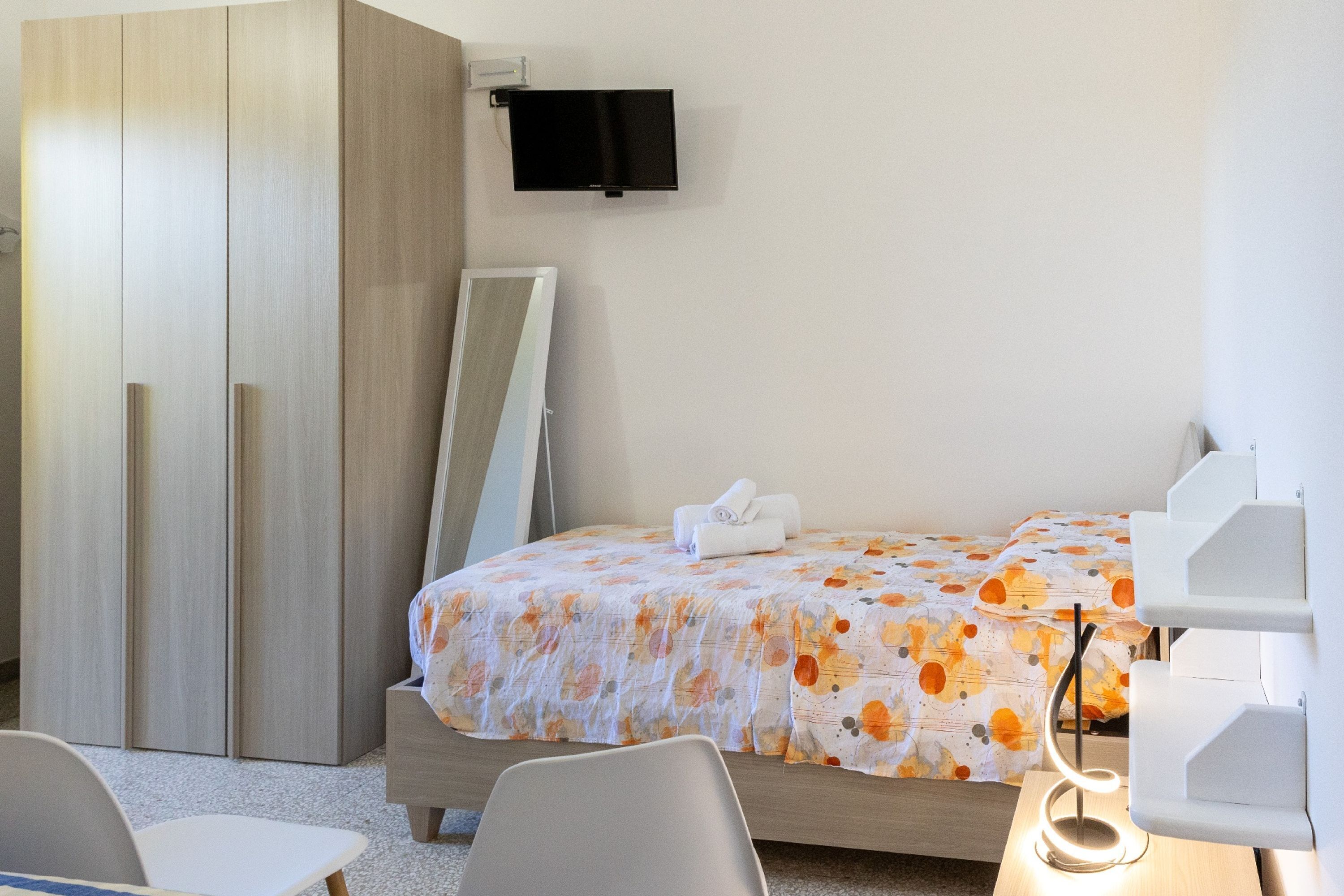 Habitación de hotel con cama, televisión montada en la pared, escritorio y una silla.