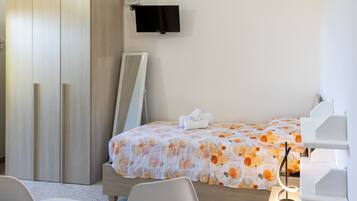 Habitación de hotel con cama, televisión montada en la pared, escritorio y una silla.