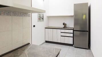 Una cocina con armarios blancos, un refrigerador de acero inoxidable y un salpicadero de azulejos.