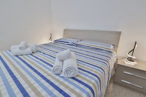 A hotel room with a bed, two bedside tables, and a wall-mounted lamp. - Casina Le Rene Con Ampio Giardino e Piscina Privata (Poggiardo)