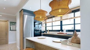 A modern kitchen with a stainless steel refrigerator, double ovens, and a large island with stools. - Genteel Home Plaza San Francisco Malaga (Málaga)