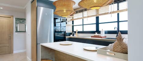 Una cocina moderna con un refrigerador de acero inoxidable, dos hornos y una isla grande con taburetes.