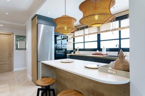 A modern kitchen with a stainless steel refrigerator, double ovens, and a large island with stools. - Genteel Home Plaza San Francisco Malaga (Málaga)