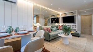 A modern living room with a dining area, a sofa set, a TV mounted on the wall, and a wooden door. - Genteel Home Plaza San Francisco Malaga (Málaga)