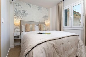 Een slaapkamer met een bed, twee bedlampen, een nachtkastje en een raam met luiken.
