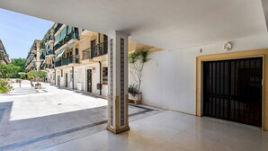 A hotel entrance with a covered walkway, a gated entrance, and a row of buildings with balconies. - Genteel Home Plaza San Francisco Malaga (Málaga)