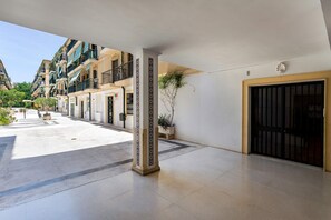 A hotel entrance with a covered walkway, a gated entrance, and a row of buildings with balconies. - Genteel Home Plaza San Francisco Malaga (Málaga)