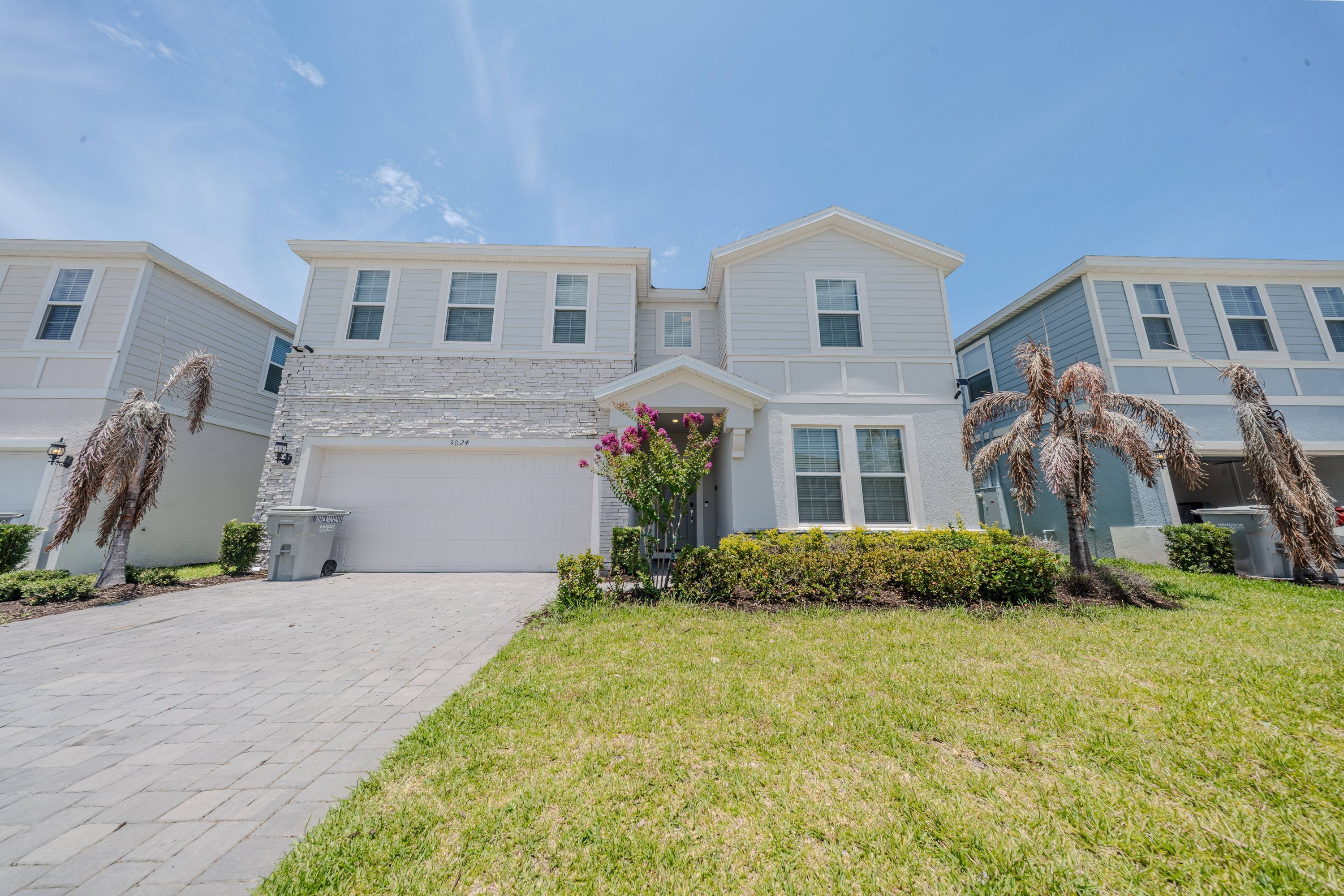 A residential building with a garage, a paved driveway, and a well-maintained lawn.