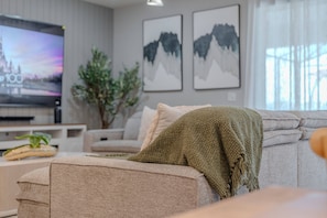 A living room with a sofa, a television, and framed artwork on the wall. - Go 37 - Windsor Island (Davenport)