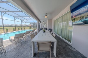 A covered outdoor dining area with a pool, chairs, and a table. - Go 37 - Windsor Island (Davenport)