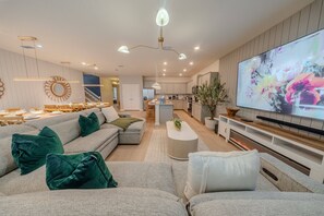 A modern living room with a sectional sofa, a flat-screen TV, and a kitchen in the background. - Go 37 - Windsor Island (Davenport)