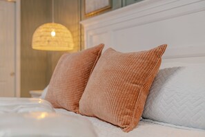 Una cama con dos almohadas y una colcha acolchada blanca.