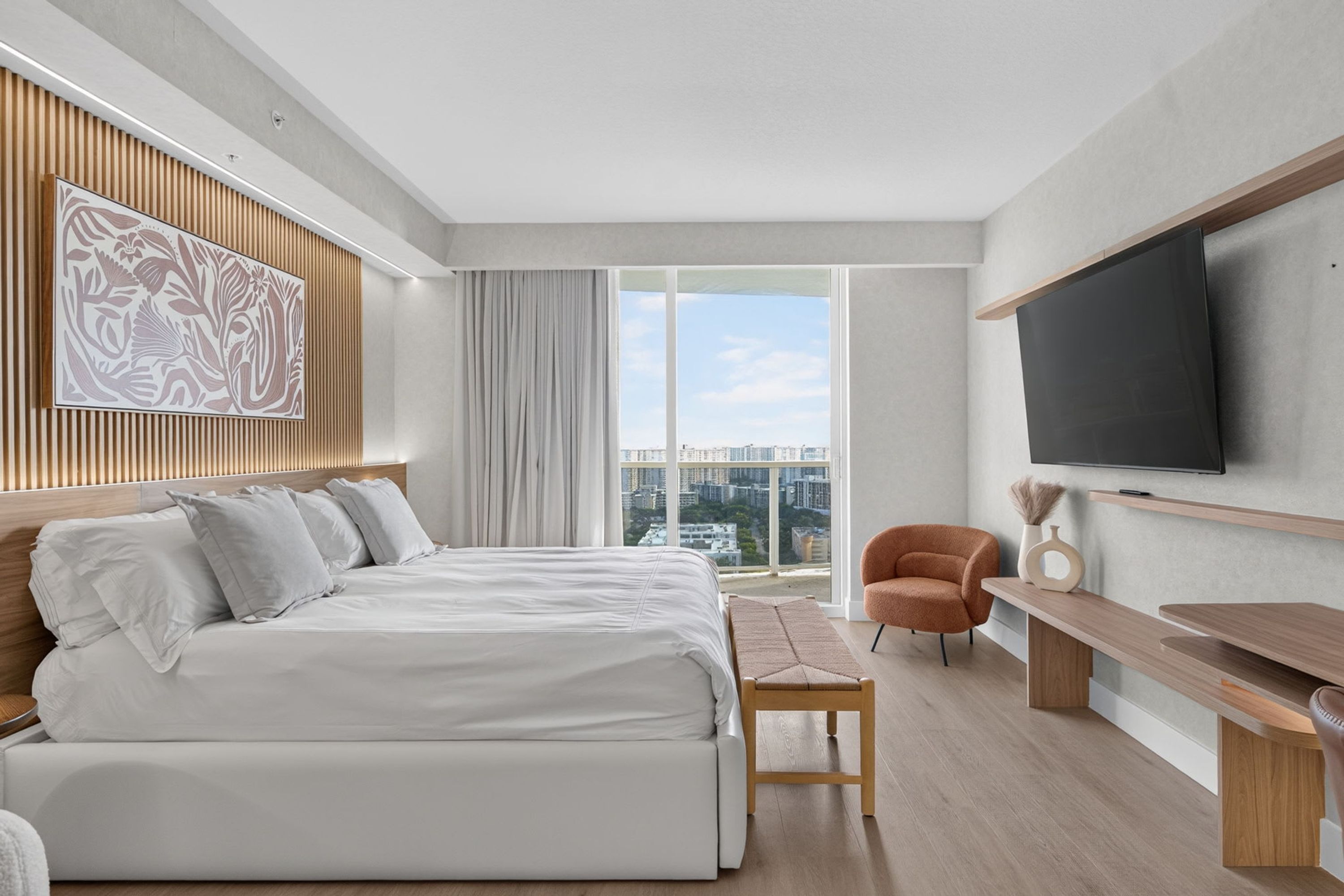 Une chambre d’hôtel moderne dotée d’un grand lit, d’une télévision, d’une vue sur la ville et d’un mur décoratif en bois.