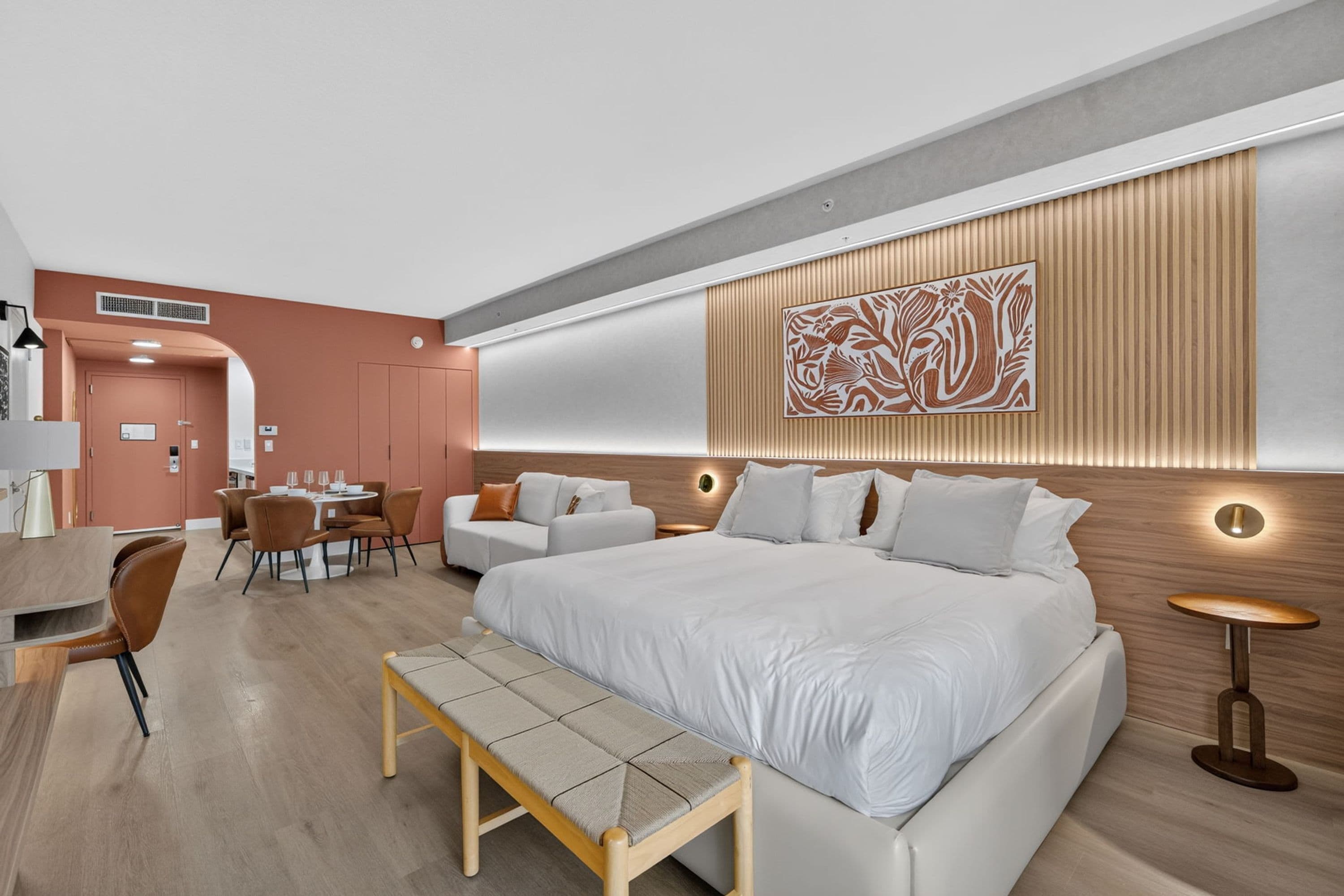 Une chambre d’hôtel moderne dotée d’un grand lit, d’un coin salon avec une table et d’un panneau décoratif mural.