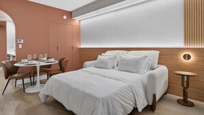 Una habitación de hotel moderna con una cama, una mesa de comedor redonda y sillas.
