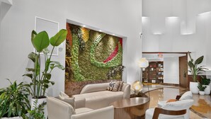 Un vestíbulo moderno con un sofá color beige, una mesa de centro y plantas en macetas.