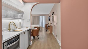 A modern kitchen with a dishwasher, a sink with a gold faucet, and a countertop with glassware. - Luxury Beachfront Escape Sunny Isles (Sunny Isles Beach)