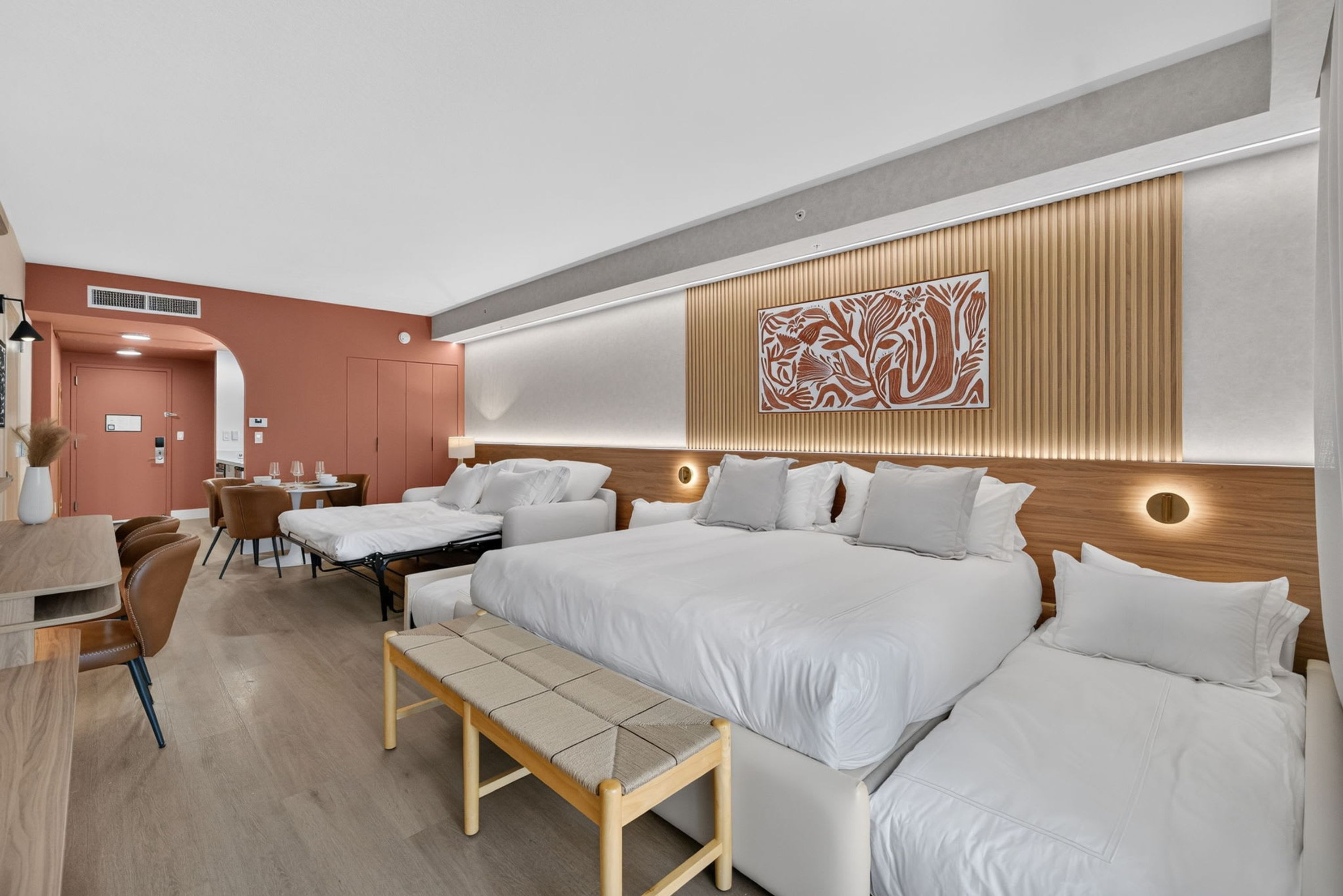 A modern hotel room with a large bed, a desk, and a dining area.