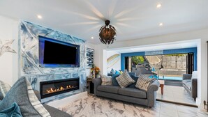 A modern living room with a fireplace, a large flat-screen TV, and a sofa. - Vitamin Sea - Swimming Pool Hot Tub Sea Views (Saundersfoot)