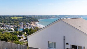 A coastal town with a view of the sea, a white building with a sloped roof, and a mix of residential and commercial buildings. - Vitamin Sea - Swimming Pool Hot Tub Sea Views (Saundersfoot)