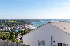 A coastal town with a view of the sea, a white building with a sloped roof, and a mix of residential and commercial buildings. - Vitamin Sea - Swimming Pool Hot Tub Sea Views (Saundersfoot)
