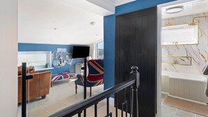 A modern living room with a large window, a flat-screen TV, and a sofa with a Union Jack cushion. - Vitamin Sea - Swimming Pool Hot Tub Sea Views (Saundersfoot)