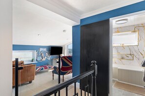 A modern living room with a large window, a flat-screen TV, and a sofa with a Union Jack cushion. - Vitamin Sea - Swimming Pool Hot Tub Sea Views (Saundersfoot)