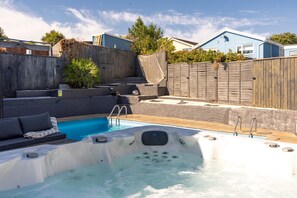 A backyard with a swimming pool, hot tub, and outdoor seating area. - Vitamin Sea - Swimming Pool Hot Tub Sea Views (Saundersfoot)