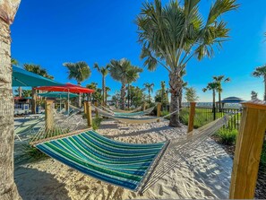 Eine Hängematte und ein Strandbereich mit Palmen und blauem Himmel.