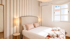Une chambre d’hôtel avec un lit, une table de chevet, une lampe et une fenêtre avec des rideaux.