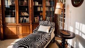 Une pièce avec un canapé à motifs zébrés, une bibliothèque en bois et une lampe.