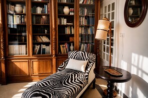 A room with a zebra-patterned sofa, a wooden bookshelf, and a lamp. - Genteel Home Bartolom de Medina (Seville)