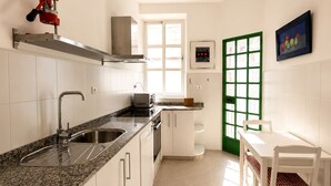 Une cuisine avec des meubles blancs, un plan de travail en granit, un évier, un four à micro-ondes et une porte dont le cadre est vert.