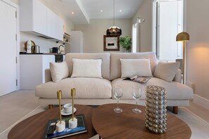 Ein modernes Wohnzimmer mit einem beigen Sofa, einem Couchtisch mit Buch und Fernbedienung sowie einer dekorativen Vase.