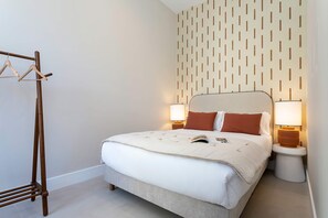 A neatly made bed with a white duvet, two pillows, and a book on it. There are two bedside lamps on either side of the bed. - Genteel Home San Anton 104 (Granada)