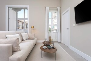 Een moderne woonkamer met een bank, een salontafel en een aan de muur bevestigde televisie.