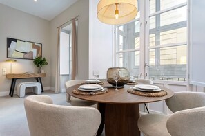 A dining area with a round table set for four, surrounded by woven chairs, a pendant light, and a large window with a view. - Genteel Home San Anton 101 (Granada)
