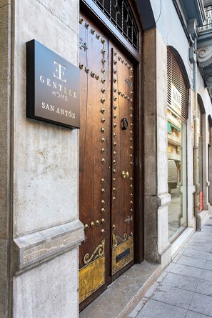 A hotel entrance with a large wooden double door, a sign above it, and a stone wall. - Genteel Home San Anton 101 (Granada)