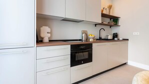 Una cocina moderna con armarios blancos, una encimera negra y un horno empotrado.