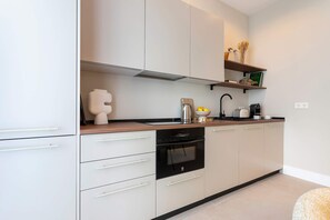 A modern kitchen with white cabinetry, a black countertop, and a built-in oven. - Genteel Home San Anton 102 (Granada)