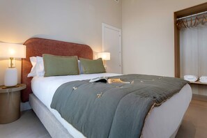 A neatly made bed with a grey blanket and two pillows, a bedside table with a lamp, and a window with curtains. - Genteel Home San Anton 102 (Granada)