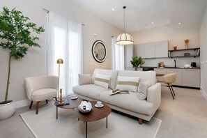 A modern living room with a sofa, armchairs, a coffee table, and a dining area with a kitchen in the background. - Genteel Home San Anton 102 (Granada)