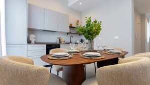 Un comedor moderno con una mesa de madera dispuesta para cuatro personas, rodeada de sillas tejidas.