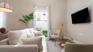 A modern living room with a sofa, a coffee table, a TV mounted on the wall, and a door leading to an outdoor area. - Genteel Home San Anton 103 (Granada)