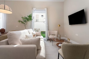 Ein modernes Wohnzimmer mit einer Couch, einem Couchtisch, einem an der Wand montierten Fernseher und einer Tür zu einem Außenbereich.