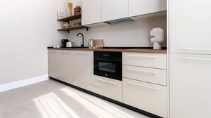 A modern kitchen with a dishwasher, oven, and a coffee maker on the counter. - Genteel Home San Anton 103 (Granada)