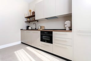 Eine moderne Küche mit Geschirrspüler, Backofen und Kaffeemaschine auf der Arbeitsplatte.
