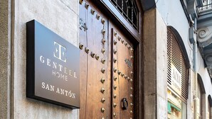 A hotel entrance with a large wooden double door, a sign above it, and a stone wall. - Genteel Home San Anton 103 (Granada)