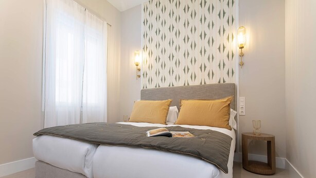 A modern bedroom with a large bed, two bedside lamps, and a patterned wallpaper. - Genteel Home San Anton 103 (Granada)