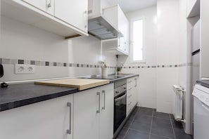 A modern kitchen with white cabinetry, a black countertop, and a tiled backsplash. - Genteel Home Reina Sof a IV (Madrid)